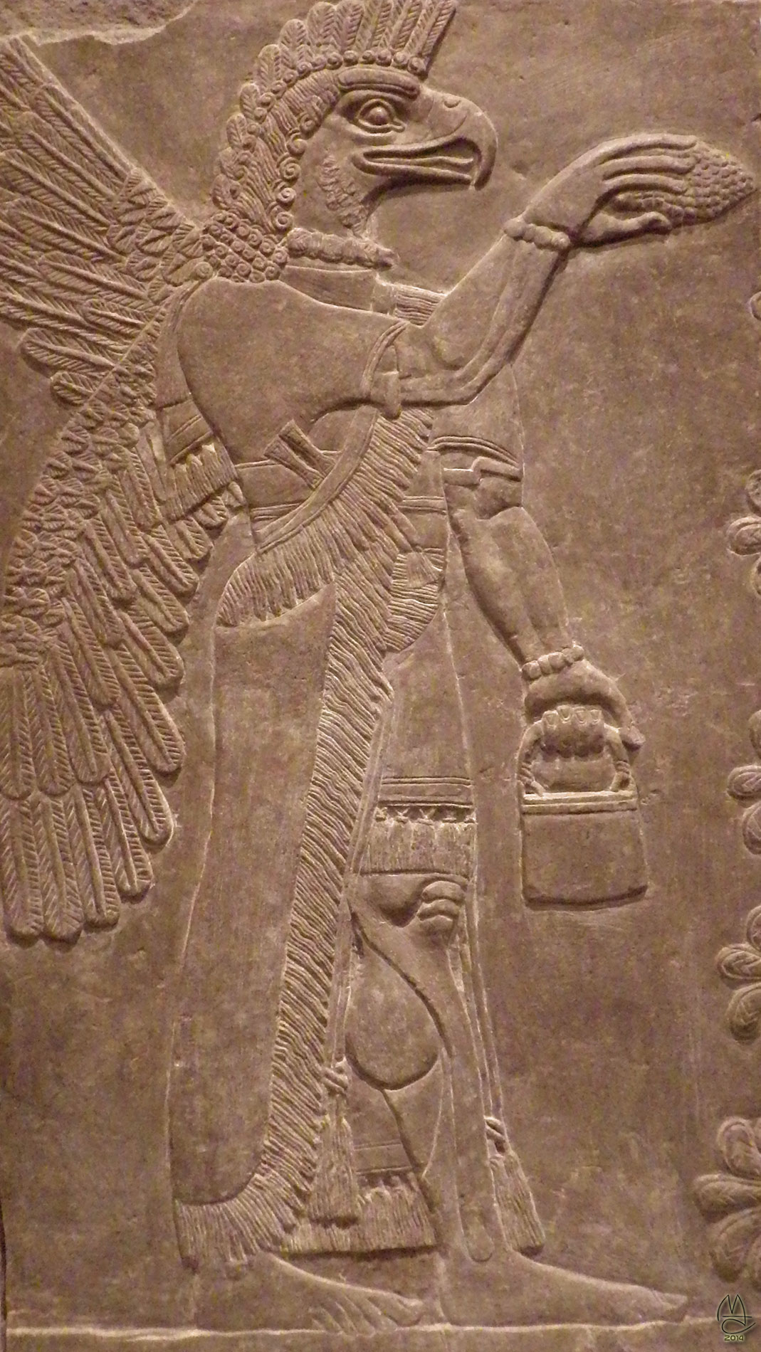 Assyrian winged god scrapes sap from a sacred palm with a pinecone. 883-859 BCE